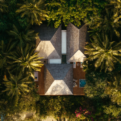 Aerial view of a luxury villa surrounded by lush palm trees, featuring a private pool.