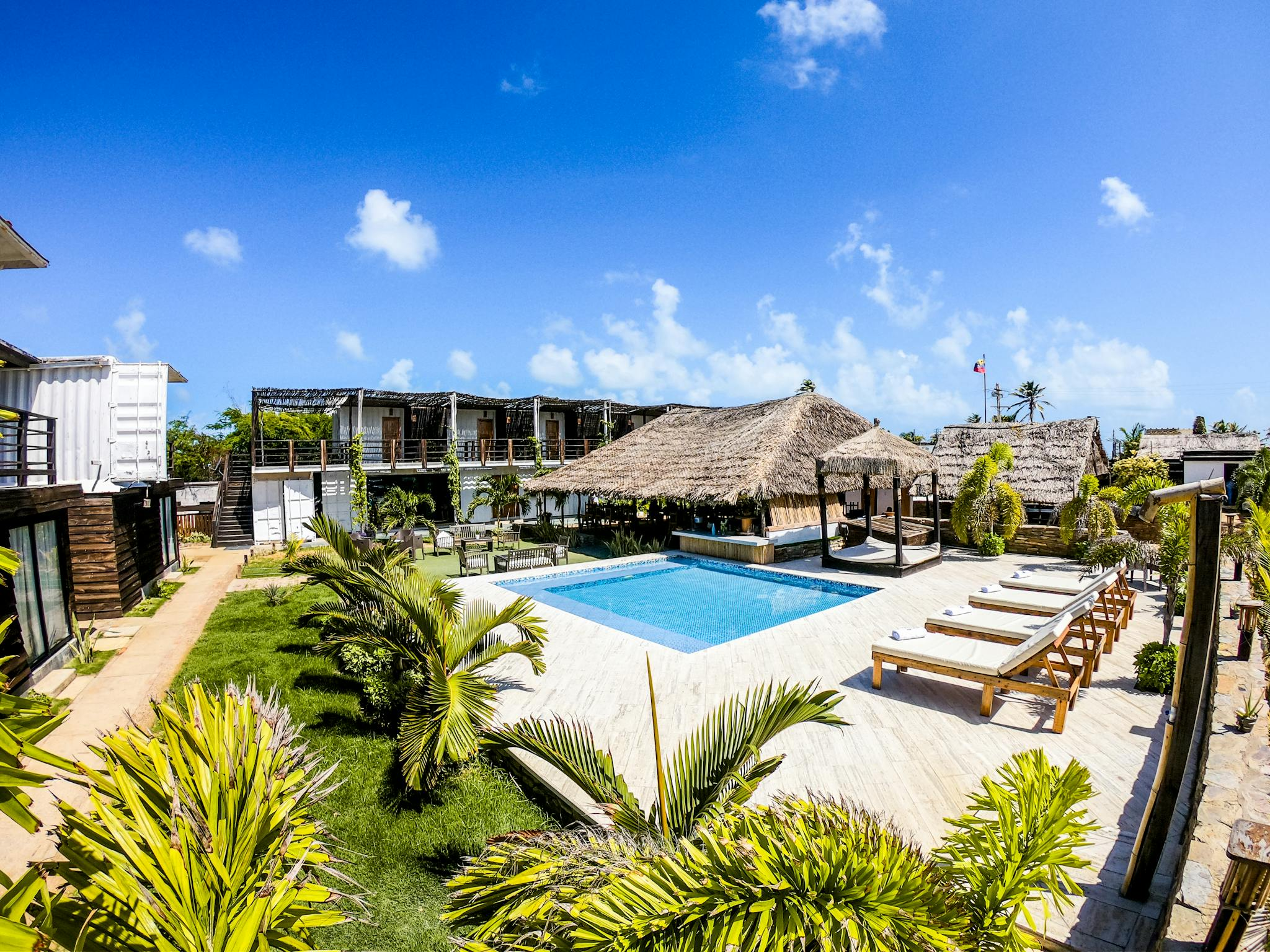 Luxurious tropical resort featuring a swimming pool and lush surroundings under a clear blue sky.
